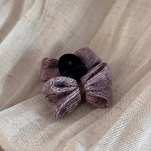 Gros plan détaillé d'une pince à cheveux nœud en tricot violet sur un fond de lin naturel