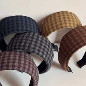 Close-up of five checkered headbands in navy, grey, brown, caramel and dark red colors