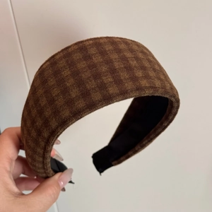 Detail shot of brown plaid wool fabric texture on a wide vintage style headband for women