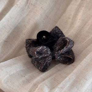 Détail de la barrette nœud en tweed avec tissage texturé et noyau velours sur tissu beige