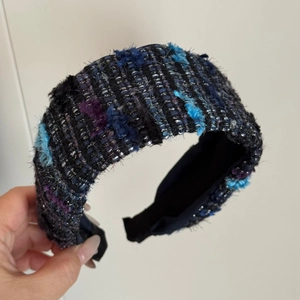 Detail of tweed headband with colorful yarn, fuzzy balls, and fringe edges
