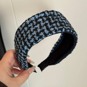 Detailed close-up of blue and black tweed fabric texture on a wide padded headband