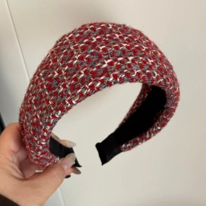 Detail of red and white tweed headband with colorful threads and black inner lining