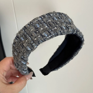 Detailed view of thick knitted tweed headband with blue-grey fabric and silver sequins