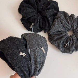 Detailed view of plush teddy bear headbands in black and grey with silver metal charms