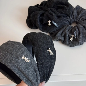 Detailed view of dark grey and black wool-textured headbands with silver bear pendants
