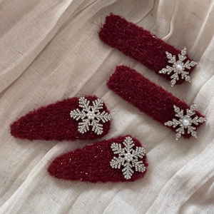 Detailed view of deep red plush hair clips with rhinestone snowflake and pearl accents