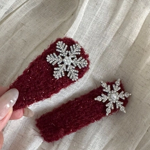 Close-up of plush wine red hair clips with silver snowflake and pearl detail