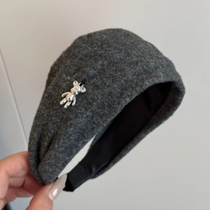 Detail of grey fleece headband featuring a cute silver metal bear charm and soft black lining