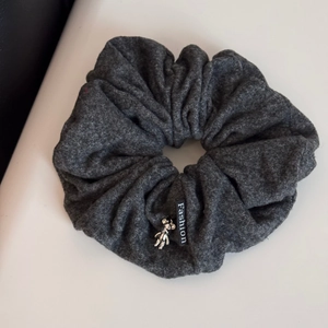 Detail of dark grey textured fabric scrunchie with silver bear charm and Fashion label