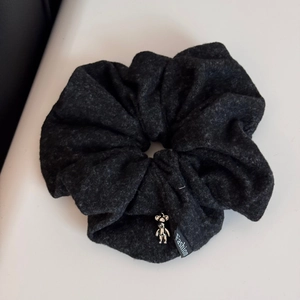Detailed macro view of dark grey velvet fabric scrunchie with metallic bear pendant decoration