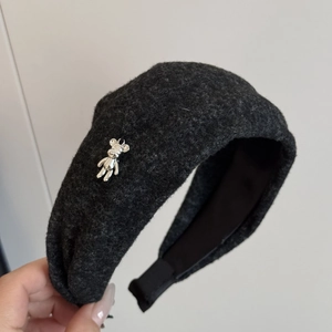 Detail of grey woolen headband featuring a cute silver bear ornament and soft texture