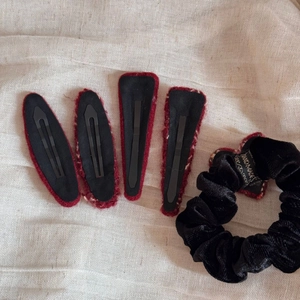 Close-up of red plaid tweed hair clips and black velvet scrunchie on linen fabric