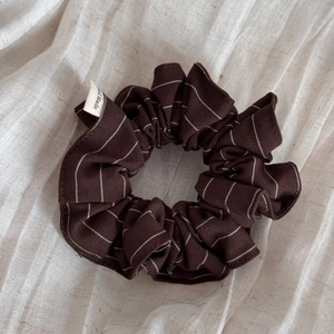 Gros plan détaillé du chouchou en tissu à rayures marron avec étiquette Hand Made