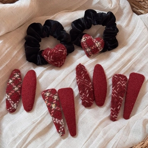 Flat lay of red plaid heart scrunchies and festive hair clips on soft beige fabric