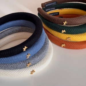 Dettaglio di cerchietti in maglia con ciondoli dorati ed etichetta Hand Made