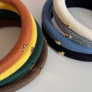 Dettaglio di cerchietti in maglia a coste con piccoli ciondoli a forma di cane dorati
