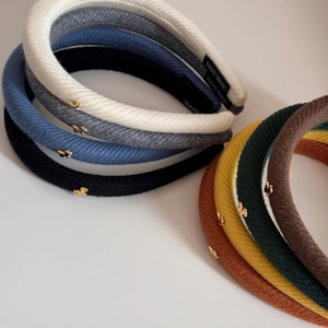 Dettagli di fasce per capelli in maglia spessa con ciondoli a orsetto dorato e etichetta