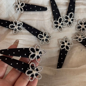 Close-up of polka dot fabric hair clip with silver rhinestone flower on soft fabric