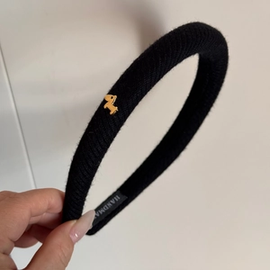 Dettaglio del cerchietto in tessuto nero con ciondolo a cane dorato ed etichetta handmade