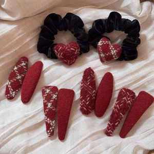 Close-up of red plaid fabric hair clips and black velvet scrunchies on white fabric