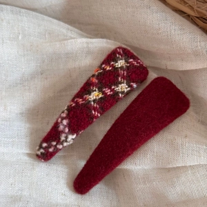 Detail of red tweed and plaid wool hair clips showing warm textile fiber texture