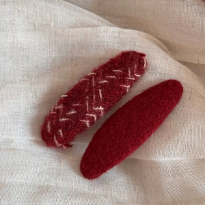 Detail showing red wool and knit fabric textures on metal BB hair clip accessories