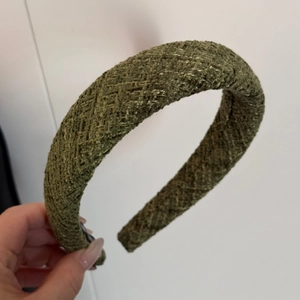 Close-up of olive green tweed headband showing premium woven texture and thick sponge padding