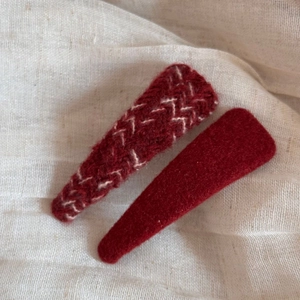 Detail of red felt hair clips set with stitching texture on ivory linen background