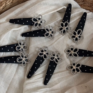 Close-up of black polka dot hair clips featuring silver hollow flowers and clear rhinestones
