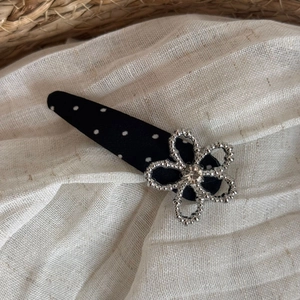 Detailed close-up of a black polka dot fabric clip with a silver rhinestone flower ornament