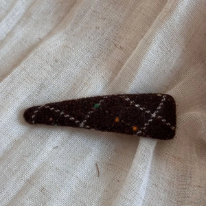 Detailed texture of dark brown tweed hair clip with white plaid and autumn vintage style
