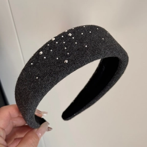 Gros plan sur un serre-tête en tricot gris foncé orné de strass argentés et design rembourré
