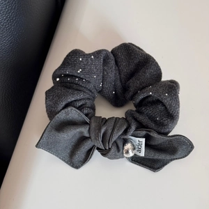 Détail d'un chouchou gris foncé avec strass argentés et un nœud en tissu texturé