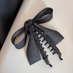 Gros plan d'une pince à cheveux à nœud gris anthracite avec perles et tissu peluche