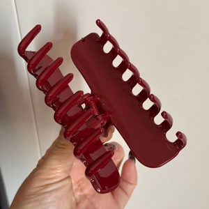 Détail d'une pince à cheveux rouge foncé brillante avec griffes et ressort robuste
