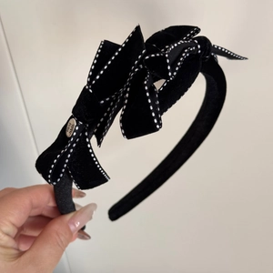 Detail of black velvet hair clip with white dotted edges and gold Hand Made label