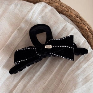 Detailed close-up of velvet bow hair claw clip with hand made silver metallic logo