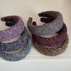 Detailed view of thick knitted plush headbands in various colors with handmade labels