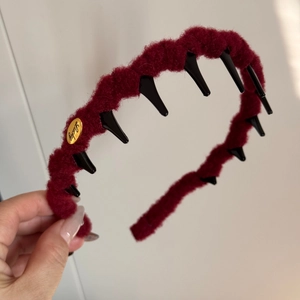 Close-up of wine red fuzzy headband featuring a golden Lucky tag and non-slip inner teeth