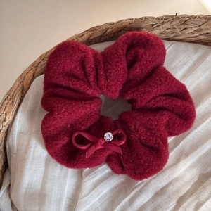 Detail of burgundy plush scrunchie with soft faux fur texture and a sparkling rhinestone bow