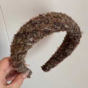 Close-up of brown plush headband with sparkling gold threads and soft knit texture