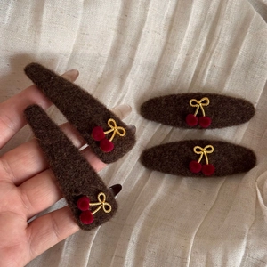 Close-up of four-piece brown felt hair clip set featuring cherry and bowknot details