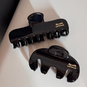 Détail de deux pinces à cheveux noir brillant avec lettrage doré Barrette LaFrance