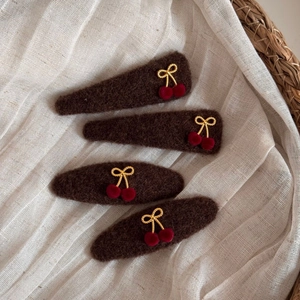 Detail of four handmade cherry bow hair clips featuring brown felt and red velvet finish