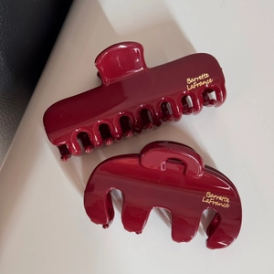 Détail de pinces à cheveux bordeaux brillant avec finition élégante en lettres dorées
