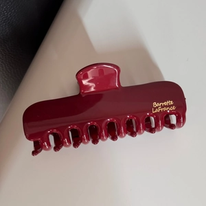 Détail d'une pince à cheveux bordeaux brillante avec lettrage doré Barrette LaFrance