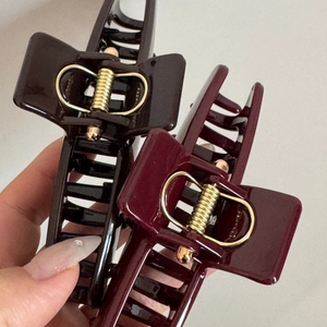 Detailed macro view of large glossy dark brown and wine red shark hair claw clips