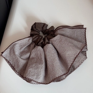 Macro shot of striped coffee and white ruffled fabric scrunchie with detailed stitching
