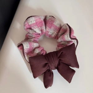 Détail d'un chouchou à carreaux rose et gris avec un nœud marron pour coiffure femme